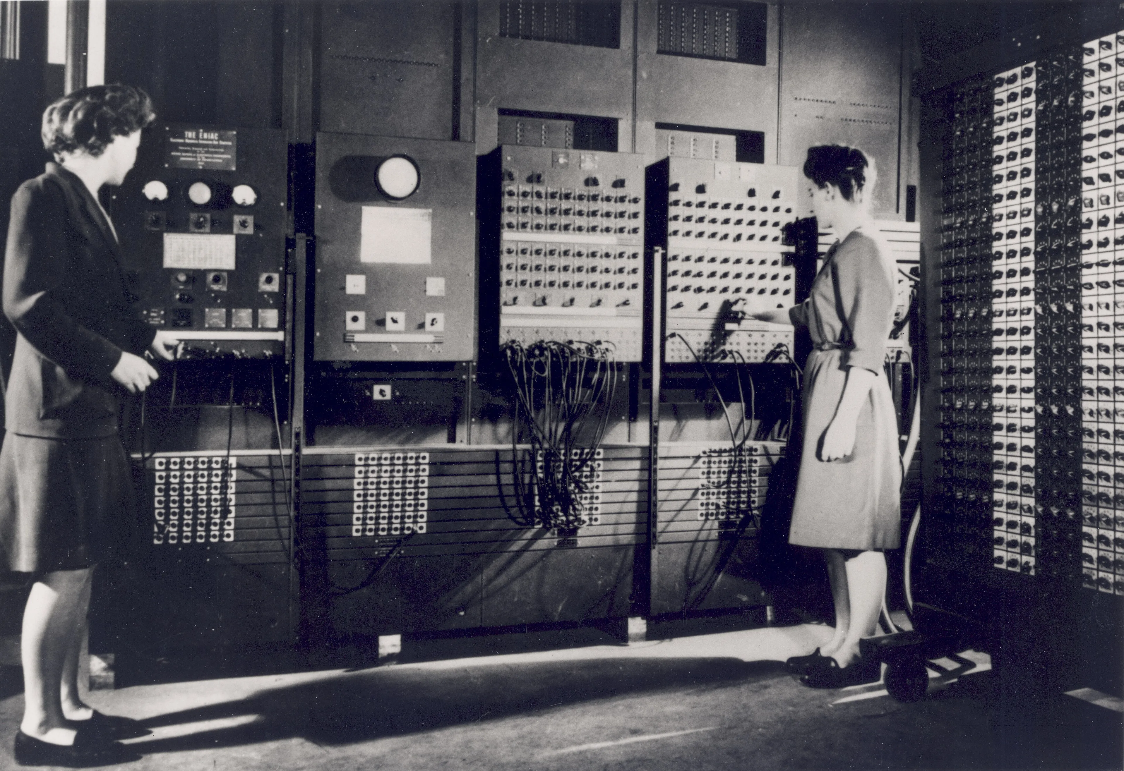 Two programmers setting switches and cables on the ENIAC computer.